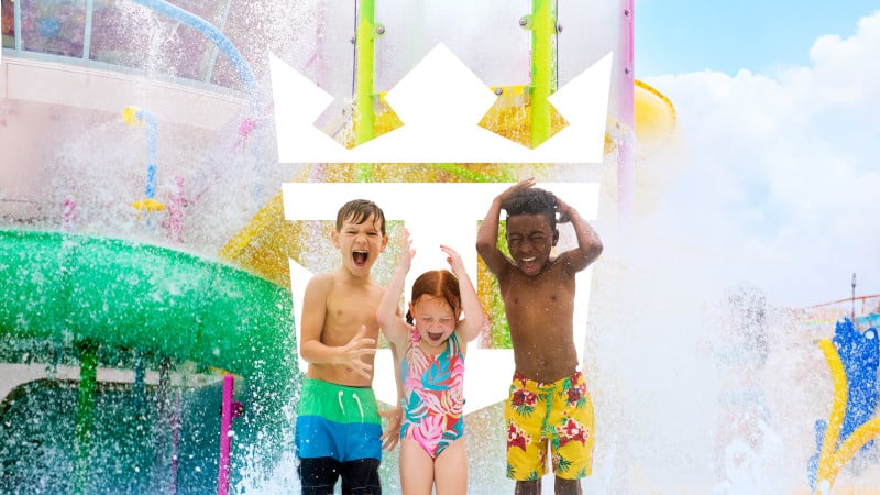 Three children laugh and play under cascading water in a colorful splash zone aboard a Royal Caribbean ship.