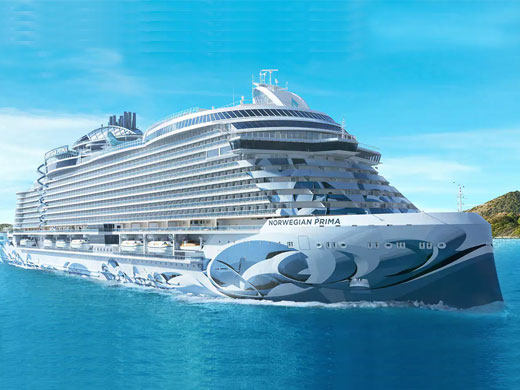 A modern, sleek Norwegian Cruise Line ship sailing on bright blue waters, featuring a distinctive white and blue hull design with curved, contemporary styling.